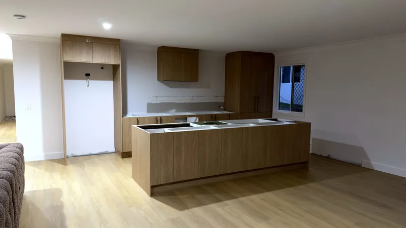 Oak-look kitchen with an island, overhead cabinet and tall units in an open-plan room