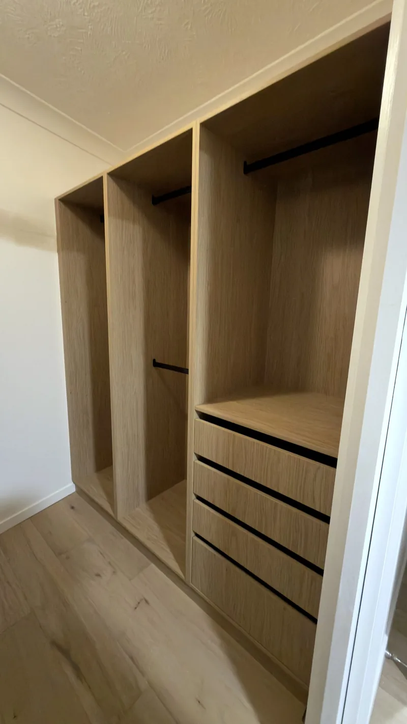 Oak wardrobe with three bays of hanging rails and a drawer bank