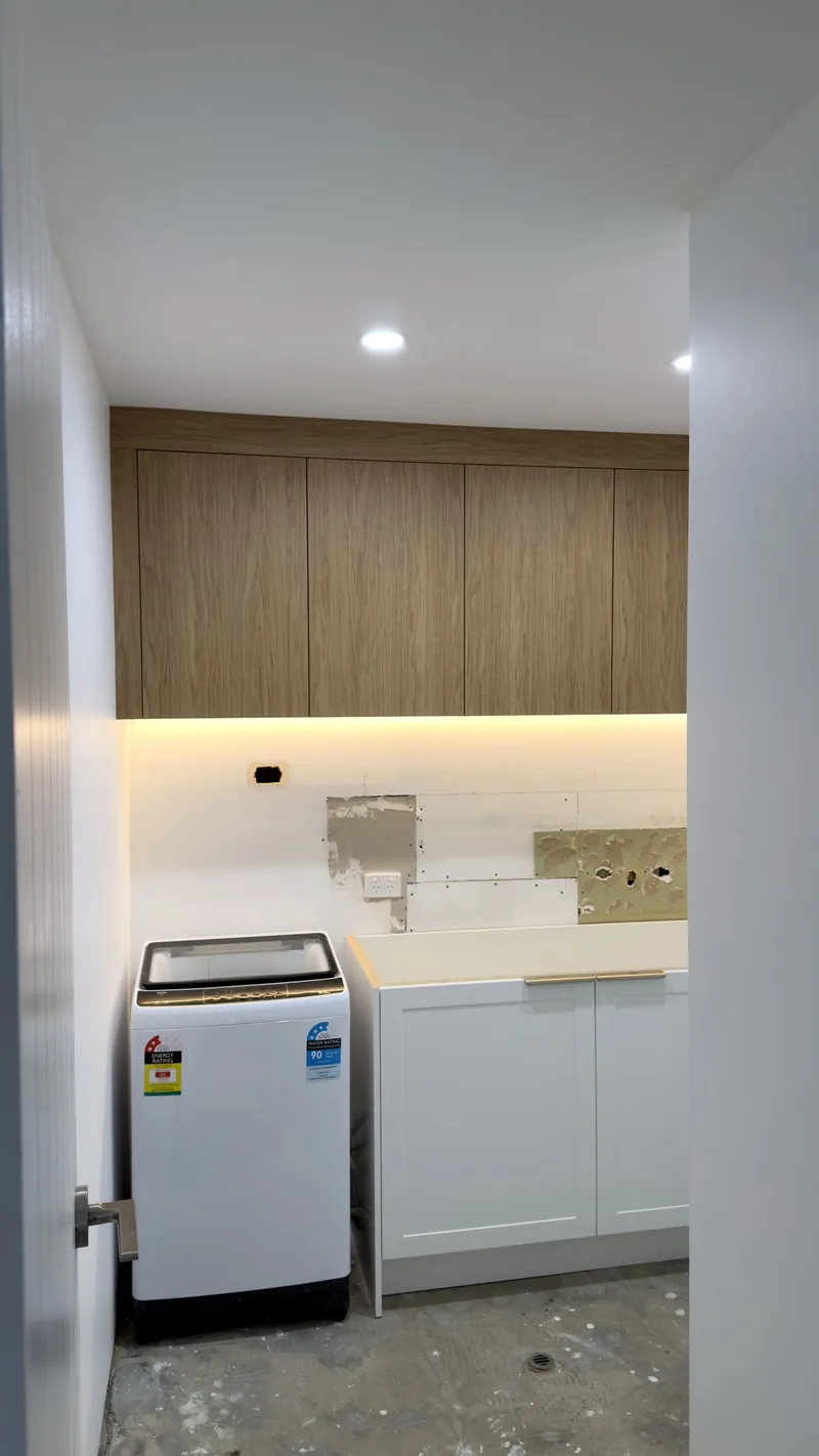 Oak overhead cabinets with an LED strip above a white shaker base cabinet, splashback not yet finished